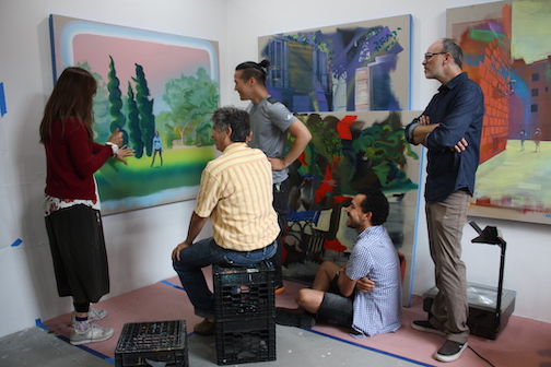 A group of five people in a room with multiple pain talking to each other